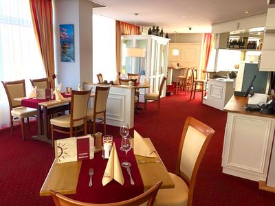 Eleganter Speiseraum mit gedeckten Tischen, roten Teppichboden und warmem Licht