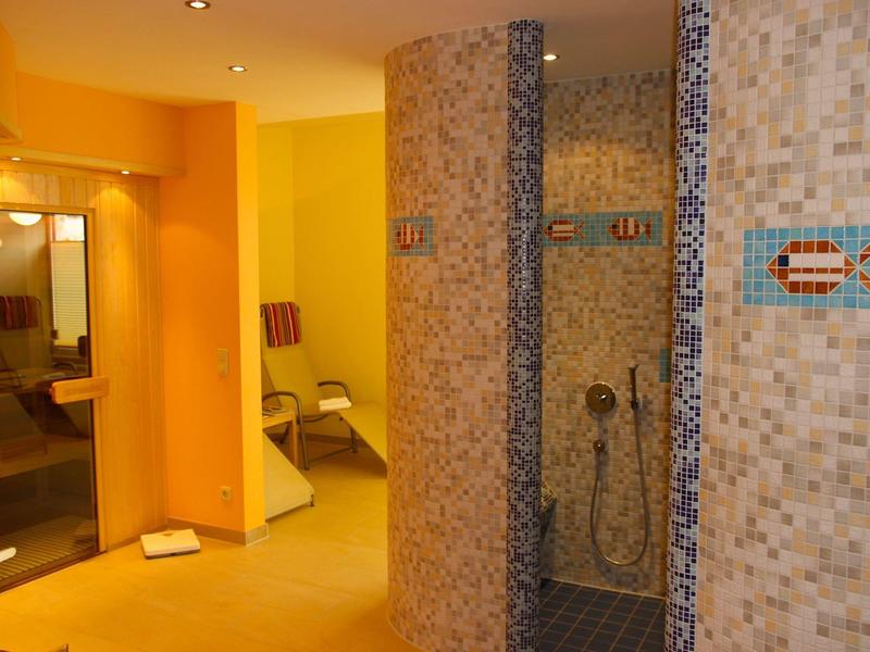 Innenbereich mit Duschen und Flur, gelb-orange Wände und gedämpftes Licht im Hotel.