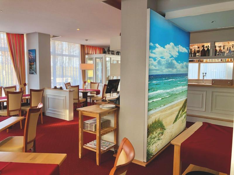 Gemütlicher Hotel-Loungebereich mit Sesseln, Tischen und einer Strandwanddekoration.