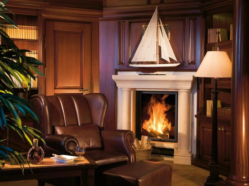Gemütliches Wohnzimmer mit braunem Ledersofa, Kaminfeuer, Holzregalen und Segelschiff-Deko.
