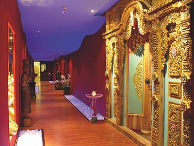 Gang met houten vloer en rijk versierde gouden deuren in een hotel.