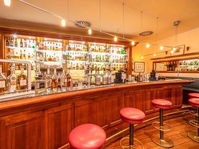 Gezellige hotelbar met rode krukken en een goed gevulde plank vol flessen.