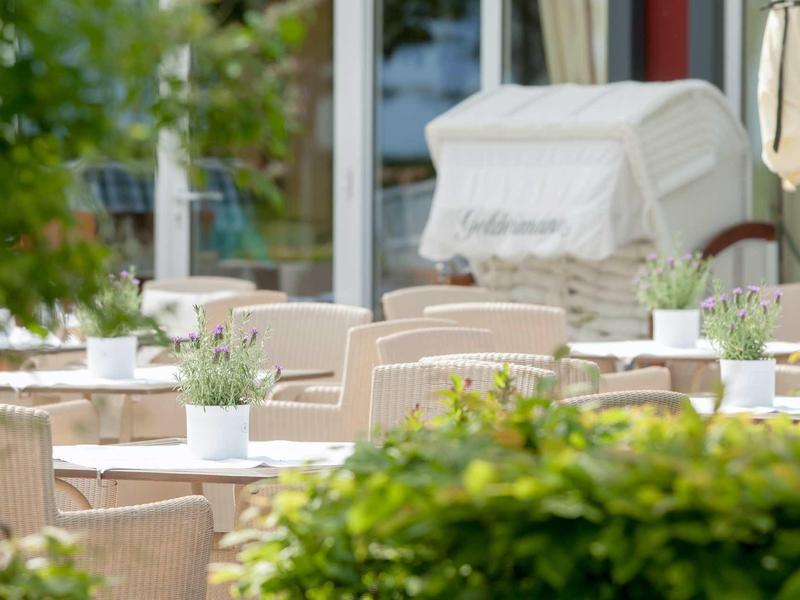 Leeg buitenterras van café met tafels, stoelen en kleine potplanten.