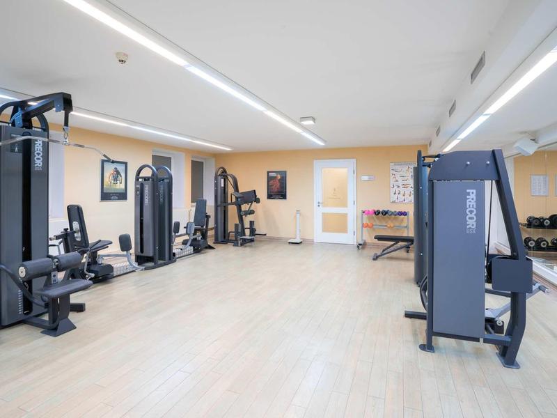 Ruime, lichte sportschool met moderne apparatuur en lichte houten vloer.