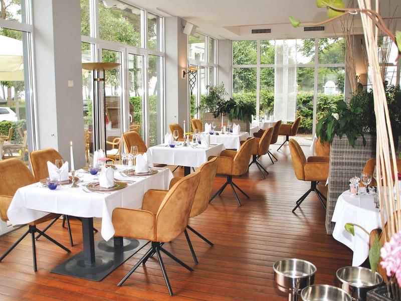 Elegant restaurant met houten vloer, bruine leren stoelen en grote ramen met uitzicht naar buiten.