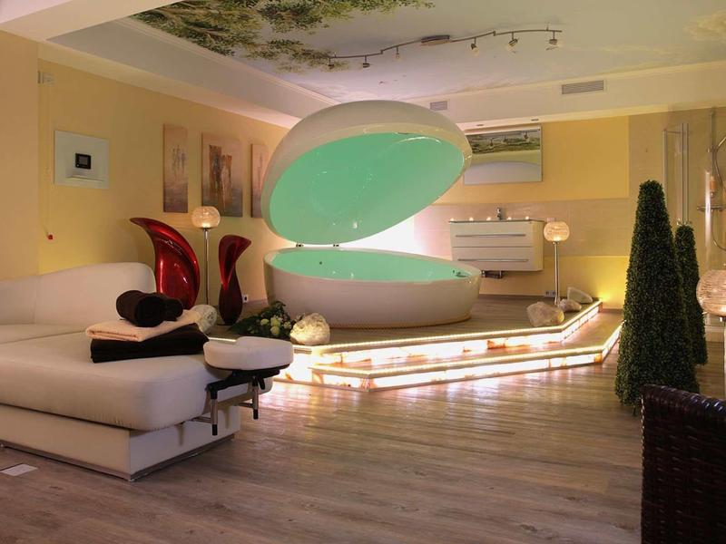 Moderner Raum mit einem großen, geöffneten, muschelförmigen Wasserkapsel-Spa und gemütlichen Sofas.