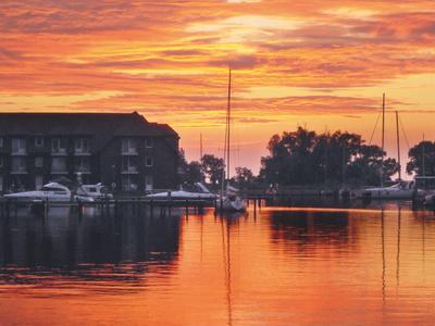 Sonnenuntergang über einem Hafen mit Segelbooten und einem Gebäude am Wasser