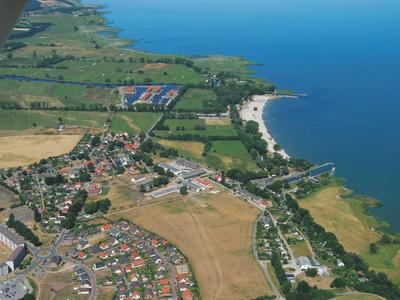 Luftaufnahme einer Küstenlandschaft mit Stränden, Feldern und einem Dorf.