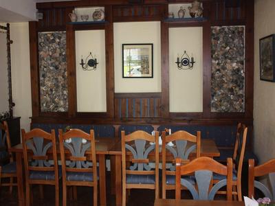 Gemütlicher Essbereich mit Holztisch, Stühlen und dunklen Holzpaneelen an der Wand.