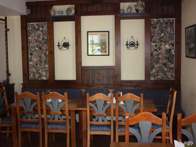 Gemütlicher Essbereich mit Holztisch, Stühlen und dunklen Holzpaneelen an der Wand.