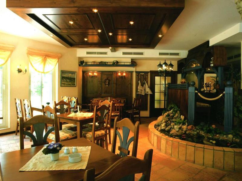 Gemütliches Restaurant mit Holzstühlen, Tischen und einem barocken Kamin als Raumteiler.