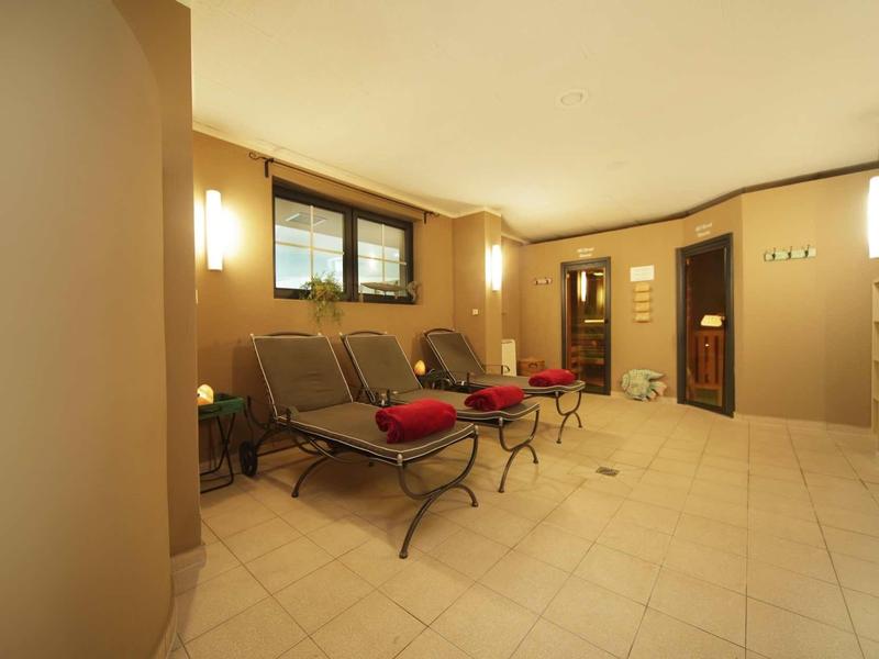 Heller, gemütlicher Zimmerbereich mit braunen Wänden, großen Fenstern und gepolsterten Stühlen mit roten Kissen.