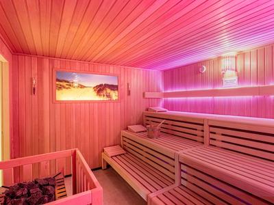 Modern gestaltete Sauna mit Holzvertäfelung und indirekter lila Beleuchtung.