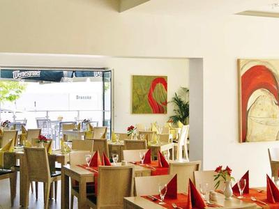 Moderní jídelna s dřevěnými židlemi, červenými ubrousky a velkým oknem.