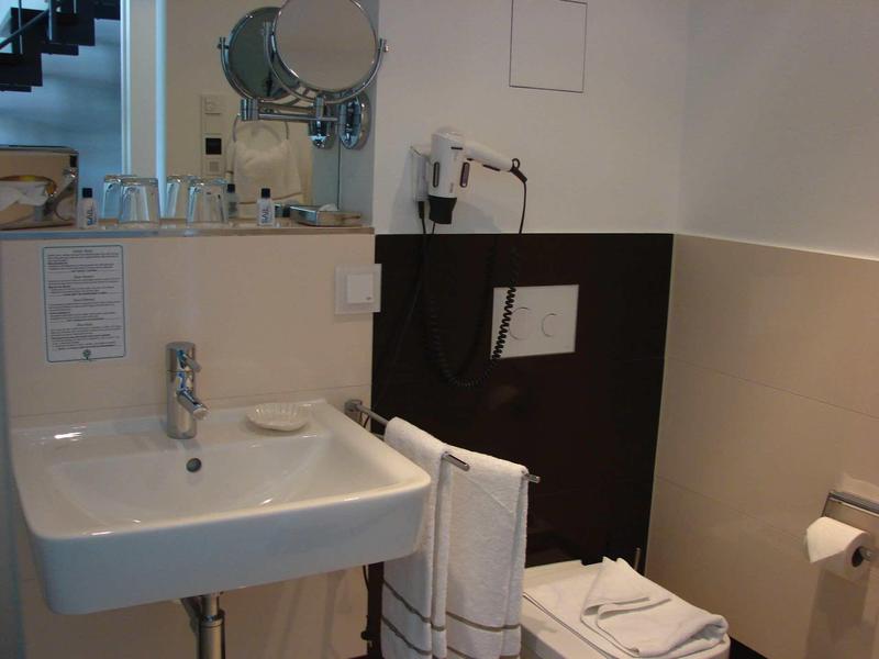 Compact bathroom with sink, mirror, towels, and hairdryer in neutral tones.