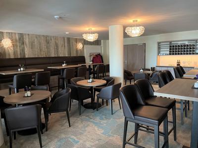 Cozy hotel lounge area with tables, chairs, and subdued lighting.