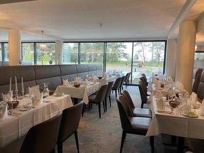 Elegant restaurant with set tables and lake view through large windows.