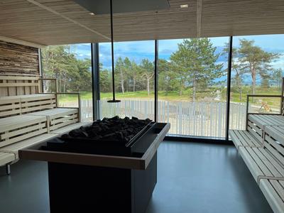 Moderner Saunainnenraum mit Holzsitzen und großem Fenster mit Blick auf Natur und See.