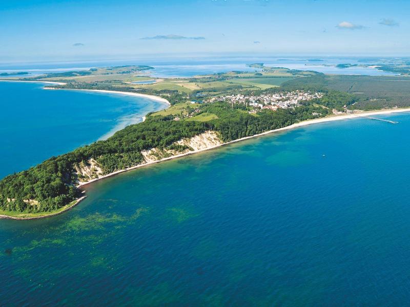 Aerial view of a forested peninsula with coastline and beaches in blue water.