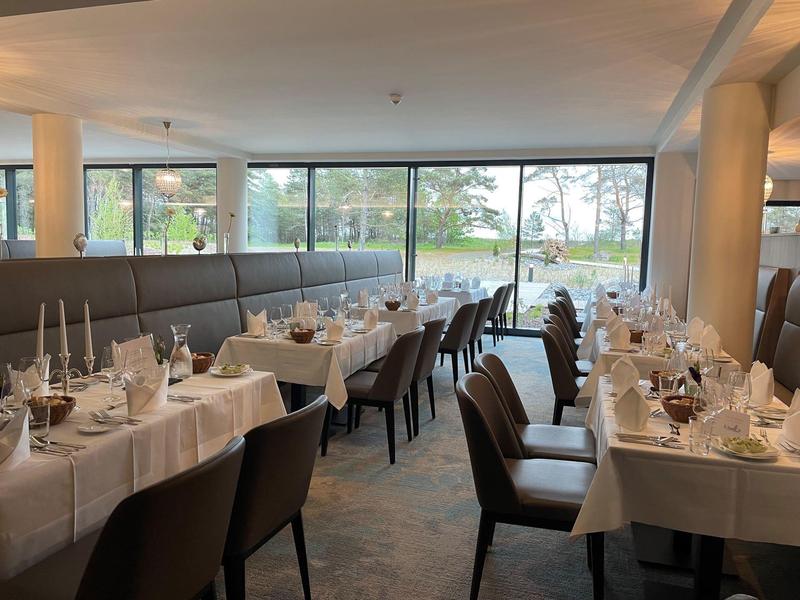Elegant restaurant with set tables and lake view through large windows.