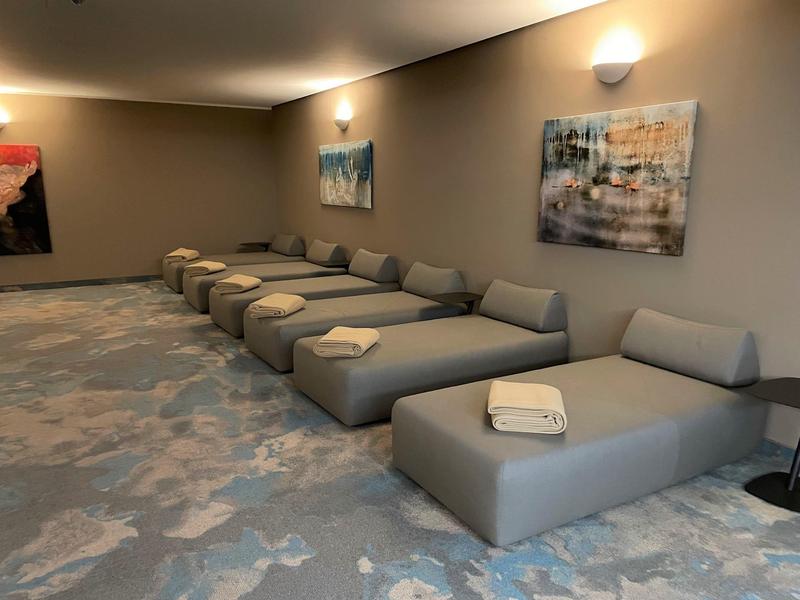 Modern relaxation area with gray upholstered furniture and towels on the wall of a spa.