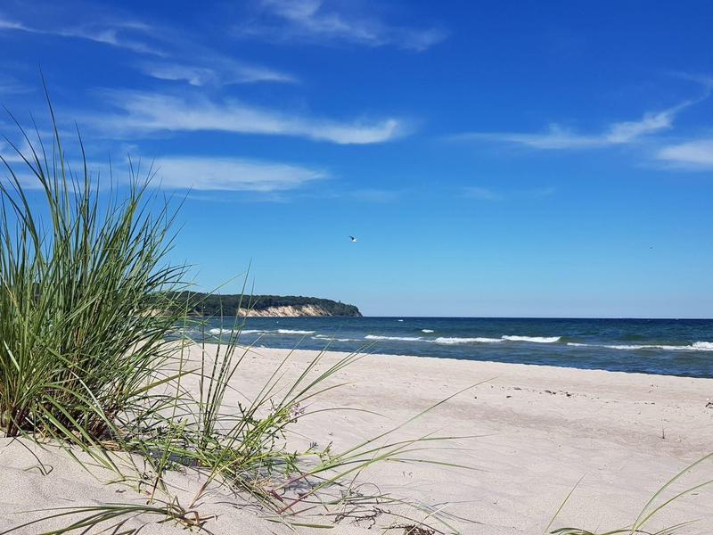 White sandy beach with dunes and sea under a blue sky.