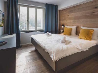 Camera d'hotel accogliente con letto grande, decorazione in legno e finestre con balcone.
