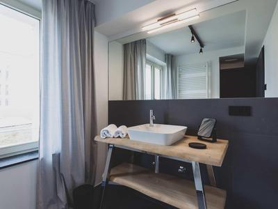 Bagno d'hotel moderno con grande specchio, lavandino su tavolo di legno e finestra con tenda