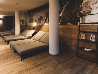 Ein ruhiger Wellnessbereich mit Liegen, warmem Licht und Holzdekor.