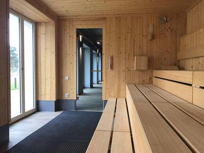 Sauna moderna con panche di legno e porte in vetro in un hotel.