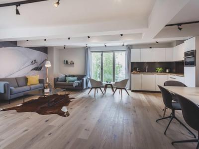 Modernes Wohnzimmer mit großem Fenster, Holzboden, Sofa, Esstisch und offener Küche