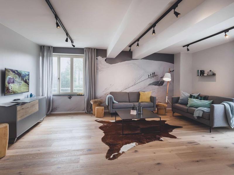 Soggiorno moderno con due divani, pavimento in legno, grande finestra, luminoso e accogliente.