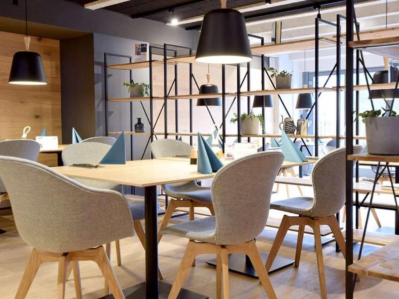 Sala da pranzo moderna con sedie di legno e scaffali decorativi in un hotel.