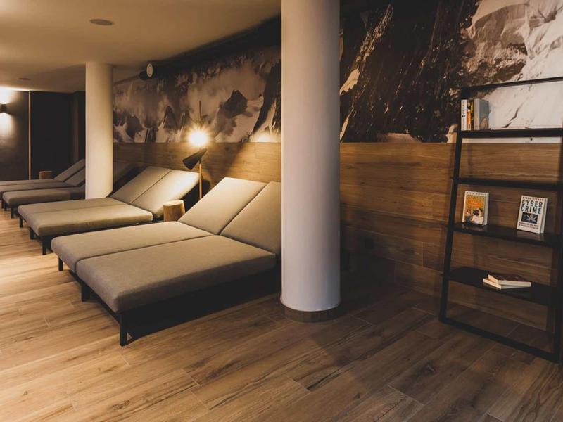 Area relax con più comodi lettini, illuminazione calda e pavimento in legno.