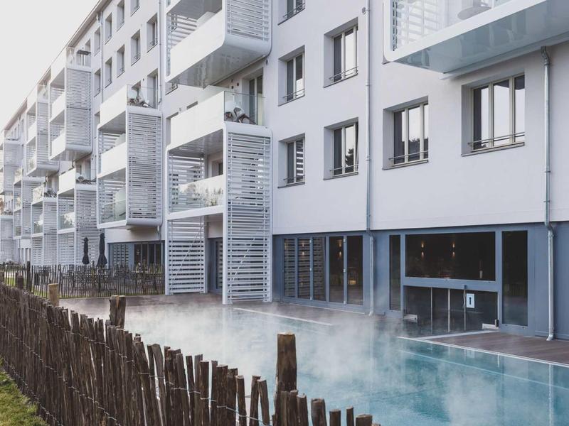 Edificio residenziale moderno con balconi e piscina esterna fumante in primo piano