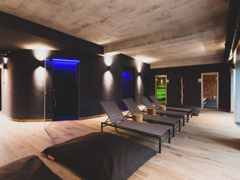 Lounge moderna con lettini e illuminazione soffusa in un'area interna elegante.