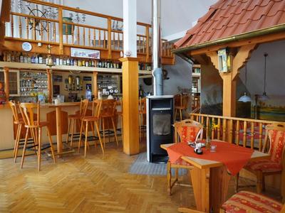 Accogliente pub di paese con bancone in legno, sgabelli e area salotto con tavolo e sedie.