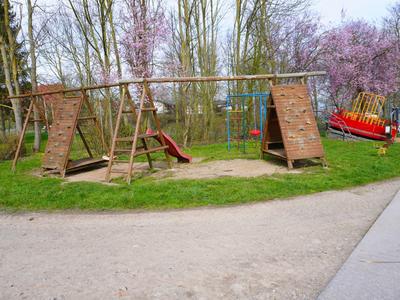 Une petite aire de jeux avec des structures d'escalade et un toboggan dans un parc au printemps.