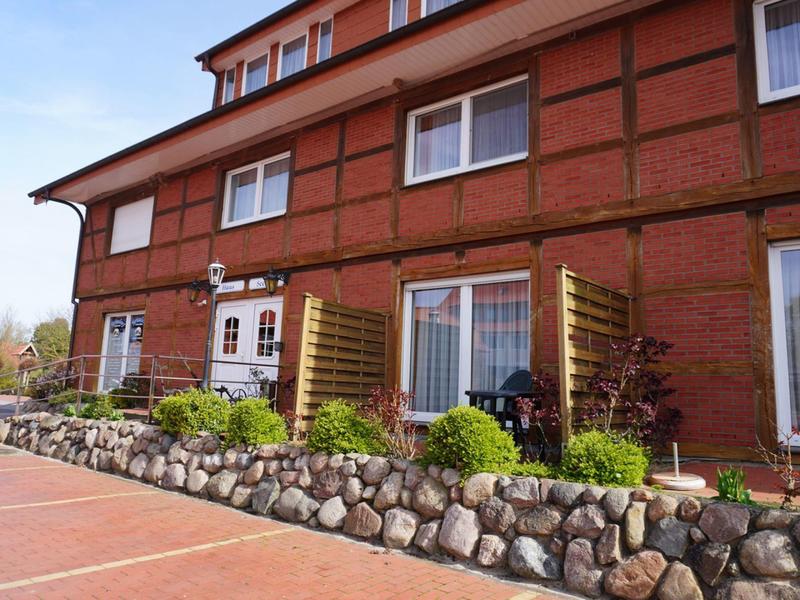 Bâtiment en briques avec plusieurs fenêtres et un petit jardin de pierres devant l'entrée
