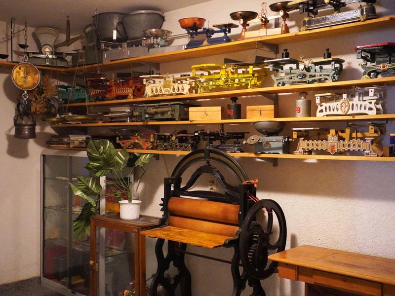 Modèles en bois et machines historiques sur des étagères dans une pièce à l'aspect muséal.