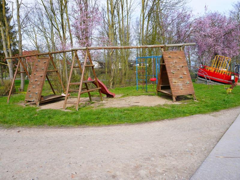 Une petite aire de jeux avec des structures d'escalade et un toboggan dans un parc au printemps.