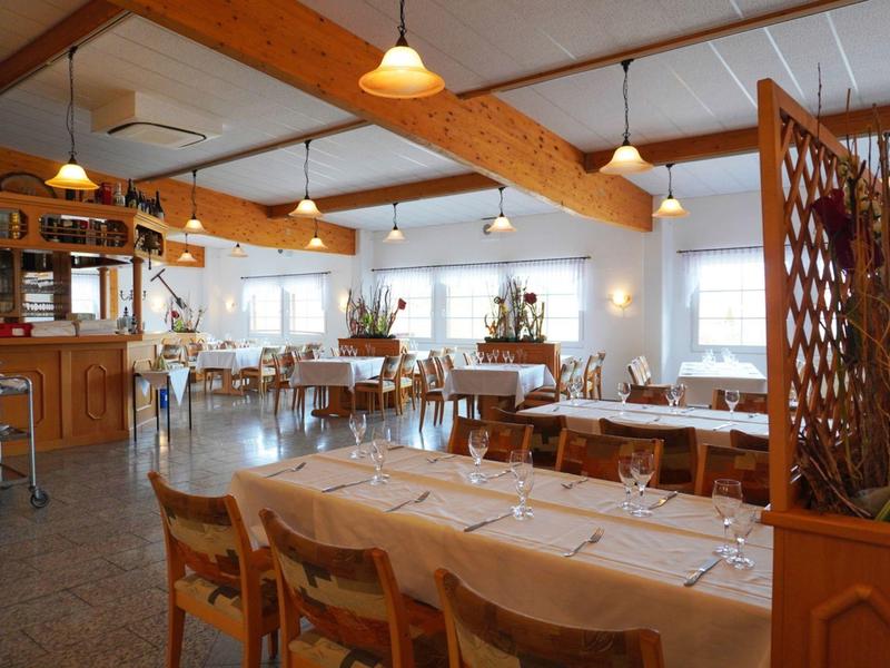 Salle à manger lumineuse et chaleureuse avec mobilier en bois et tables dressées dans un hôtel.