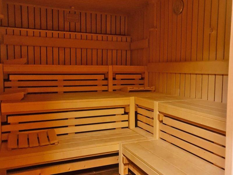 Sauna mit mehrstufigen, hellen Holzbänken und warmem Licht auf dunklem Boden.
