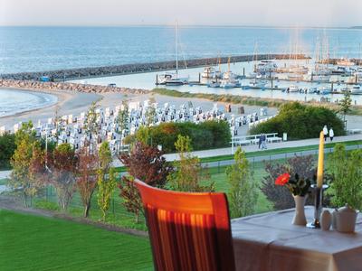 View from terrace with candle and flowers to harbor and beach at sunset
