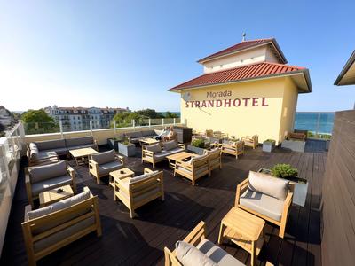 Spacious rooftop terrace with wooden furniture and sea view at the beach hotel.