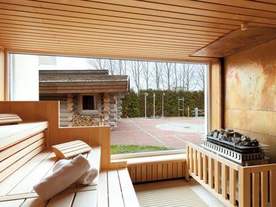Moderner Spa-Bereich mit Sauna, großen Glasfenstern und Blick auf Terrasse und Garten.