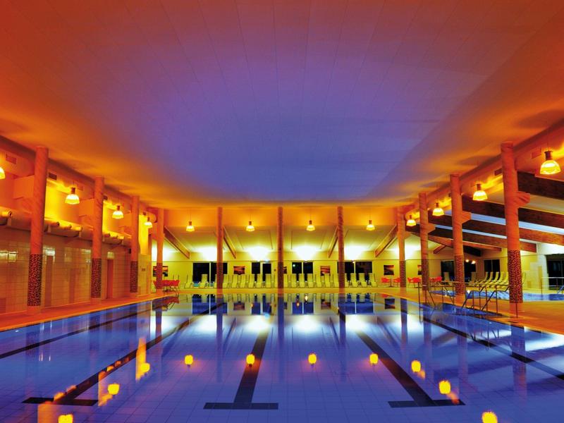 Innenbereich eines Wellnesspools mit warmem Licht und reflektierendem Wasser.