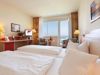 Camera d'hotel luminosa con due letti e vista sul mare