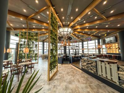 Ristorante d'hotel moderno con soffitti in legno, pareti verdi e illuminazione elegante.