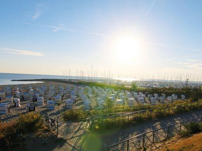 Strand mit Reihen von Liegestühlen und Sonnenschirmen, Sonnenuntergang über dem Meer